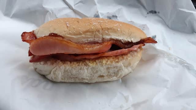 Bacon sandwich on a soft bun, resting on crumpled white paper.