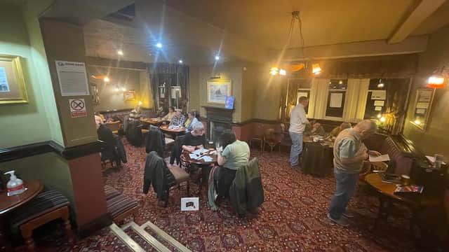 Cozy bar interior with patrons seated at tables, warm lighting, and patterned carpet in The Lobster Inn, Redcar.