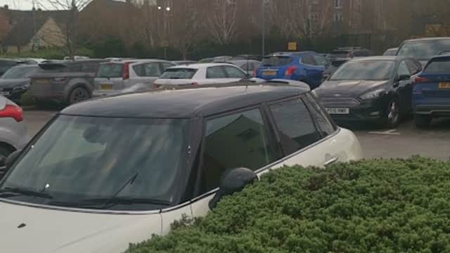 Pay & Display car park at Wortley Beck Health Centre, with parked cars and a bush in the foreground.