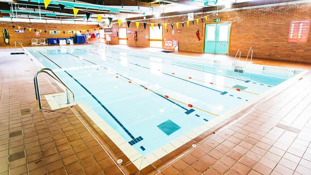 Indoor swimming pool with clear water, lane markings, and colorful bunting along the walls.