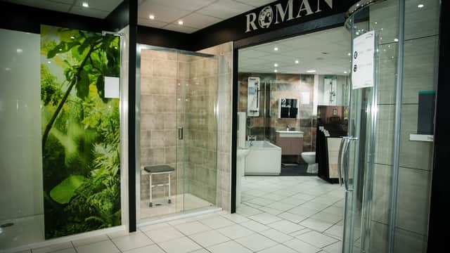 Modern bathroom display featuring a glass shower, tiled walls, and greenery mural at Windsor Bathrooms in Bradford.