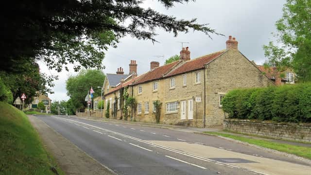 Chestnut Holiday Cottage, a stone building with a red-tiled roof, along a quiet road lined with greenery in Ebberston.
