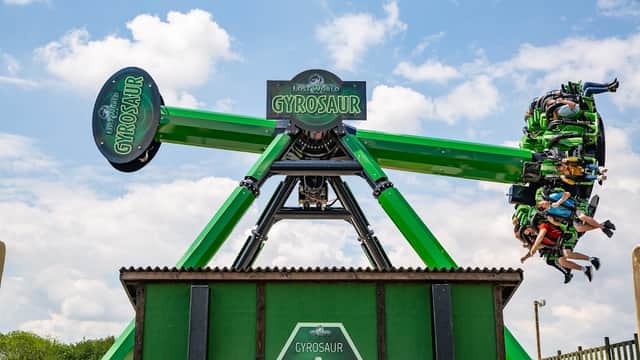 Thrilling Gyrosaur ride at Gulliver's Valley Theme Park, with excited riders suspended in the air against a blue sky.