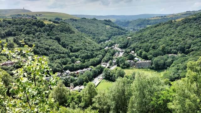 Lush green hills and valleys under a cloudy sky, with a village nestled among the trees in Chiserley, Yorkshire.