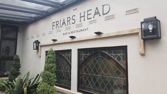 Signage for "The Friars Head" bar and restaurant, with decorative plants and stone accents.