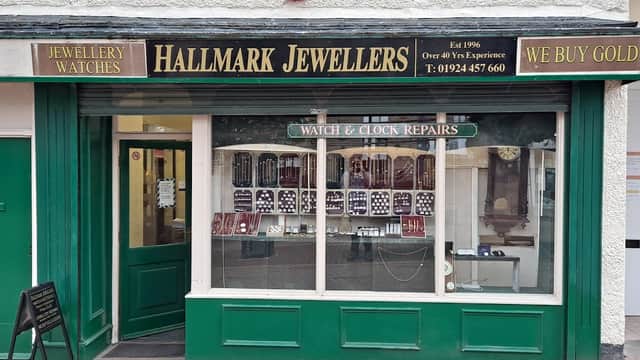 Green storefront of Hallmark Quality Jewellers, featuring displays of watches and jewellery, with a sign for repairs.
