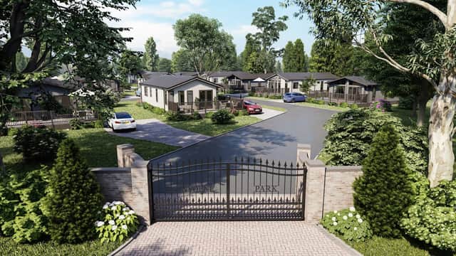 Gated entrance to Sunnydene Country Park, featuring modern lodges, landscaped greenery, and parked cars along a winding road.