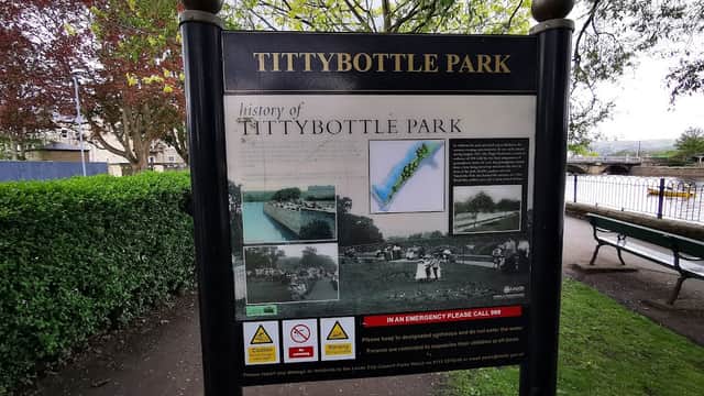 Sign for Tittybottle Park displaying its history, surrounded by greenery and benches in Otley, Yorkshire.