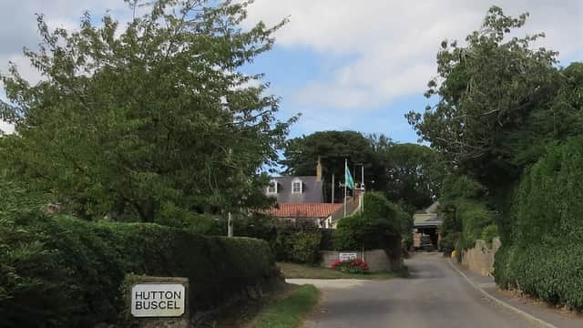 Entrance to Dale Farm Touring Park, with trees lining the road and a sign for Hutton Buscel visible.