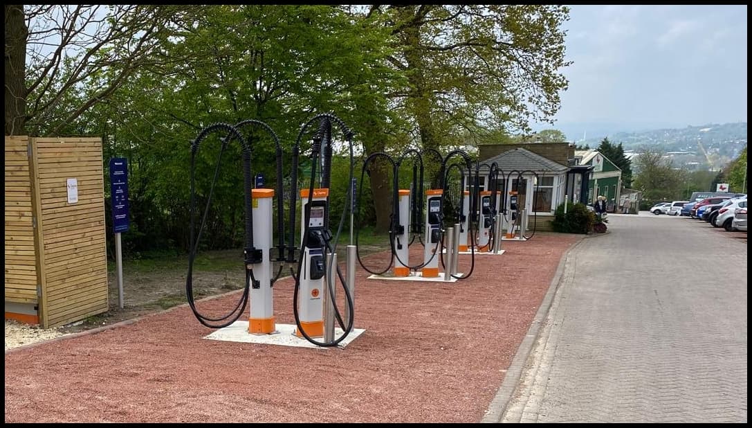 Osprey Charging Station with multiple electric vehicle chargers lined up along a gravel path in a green setting.
