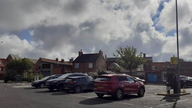 Pay & Display car park with parked cars, buildings, trees, and a cloudy sky in Selby, Yorkshire.