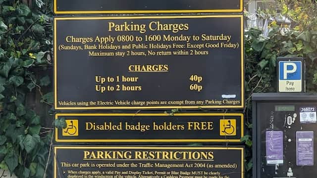 Sign for Banks Yard Car Park in Ossett, detailing parking charges, hours, and restrictions, surrounded by greenery.