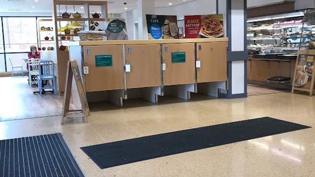 Entrance to Morrisons café with wooden counters, menu boards, and a display of pastries and drinks.