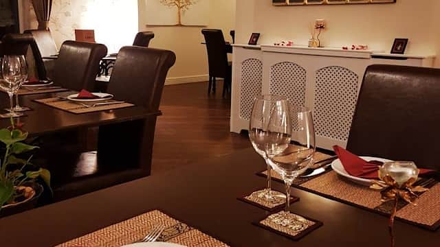 Elegant dining setup at Thai Season, featuring wooden tables, decorative trees on the wall, and neatly arranged tableware.