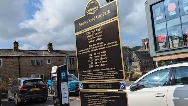 Burnley Road Car Park sign with parking fees, a payment arrow, and parked cars in Chiserley, Yorkshire.