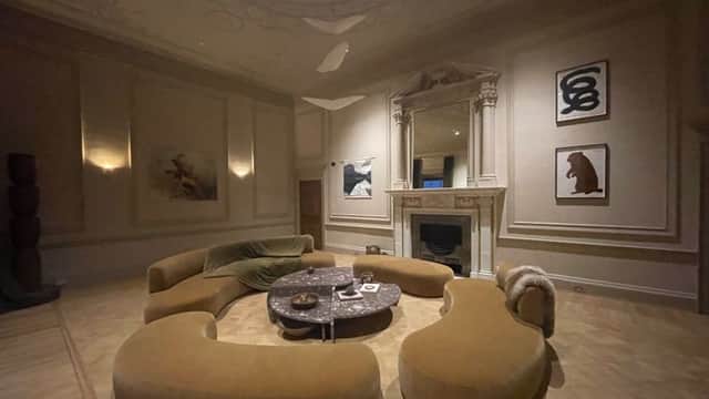 Elegant lounge area with curved sofas, a marble coffee table, and artwork on the walls, featuring a decorative fireplace.