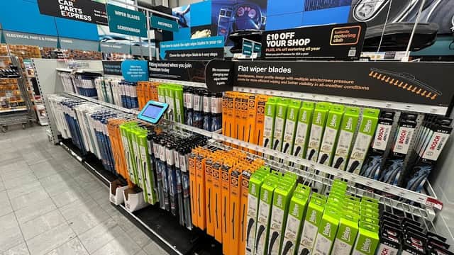 Wiper blades displayed on shelves, with promotional signage and an iPad for customer interaction in a bike shop.