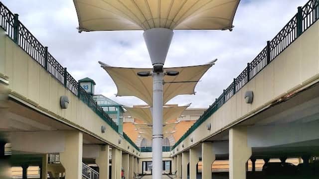 Covered walkway with large fabric canopies, leading through a multi-level car park at Meadowhall shopping centre.
