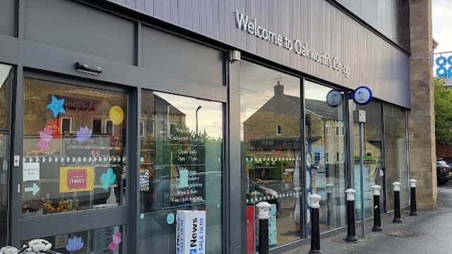 Co-op Food store entrance with signage, shopping carts, and decorative window displays in Oakworth, Yorkshire.