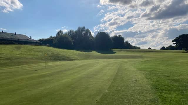 Lush green fairway at Tinsley Park Golf Course under a bright sky with scattered clouds and trees in the background.
