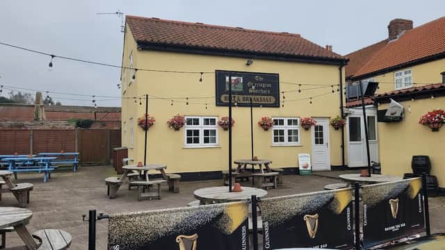 Yellow bar building with a sign, outdoor seating, flower baskets, and a Guinness banner in South Otterington, Yorkshire.