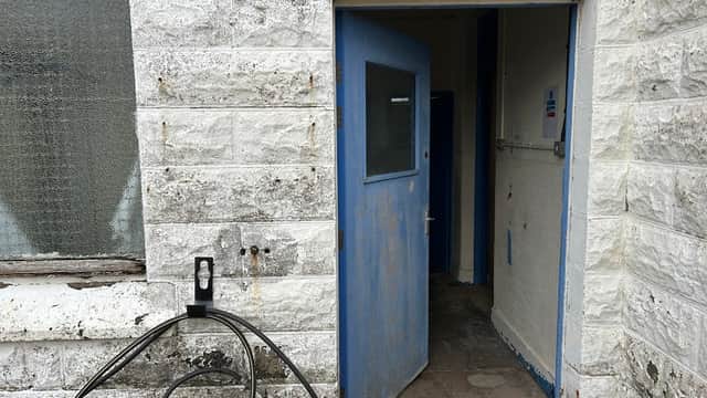 Entrance to a public toilet facility with a blue door and stone walls, located at Spurn Head, Yorkshire.