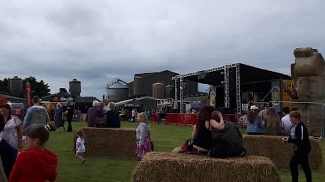 Crowd enjoying an outdoor event with hay bales and a stage in the background at Willerby Wold Piggeries Ltd.