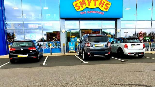 Smyths Toys Superstores storefront with large blue sign, three parked cars, and bright, inviting entrance.
