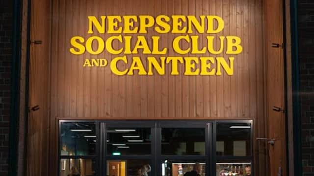 Brightly lit entrance of Neepsend Social Club & Canteen with wooden paneling and a chalkboard sign outside.