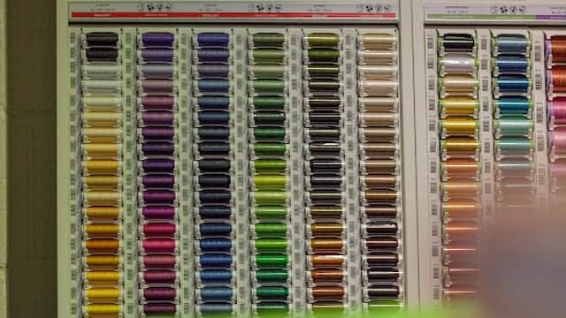 Colorful spools of thread arranged on display, showcasing a variety of hues and shades in a hobby shop setting.