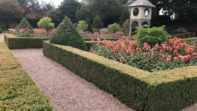 Lush garden featuring neatly trimmed hedges, colorful flower beds, and a decorative gazebo in Cullingworth, Yorkshire.