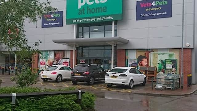 Pets at Home store with large green sign, cars parked outside, and promotional banners visible in a shopping park.