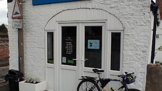 Quaint white building with blue sign "The Fat Fryer", bicycle parked outside, and decorative elements on the facade.