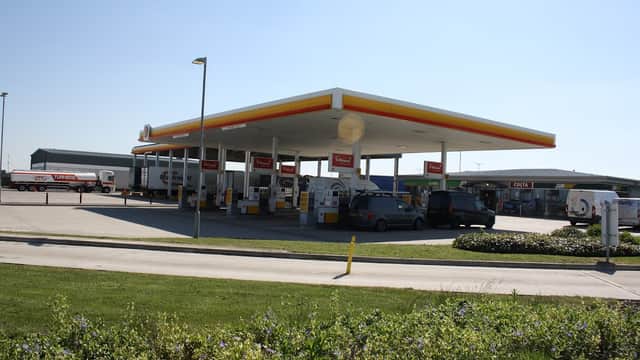 Gas station with multiple fuel pumps, trucks parked, and clear blue sky in the background.