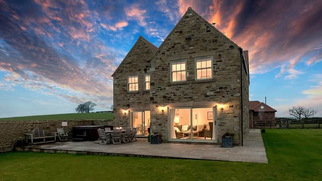 Stone farmhouse with large windows, patio area, and scenic sky at dusk in Tunstall, North Yorkshire.