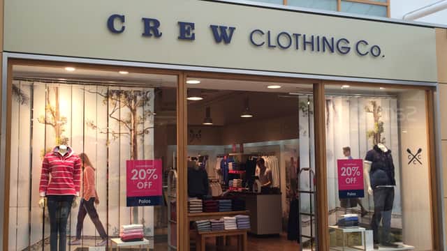 Crew Clothing Company outlet with mannequins in stylish clothing, promotional signs for 20% off, and a bright interior.