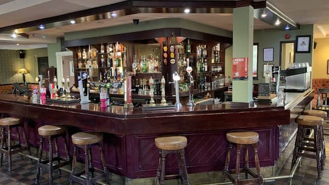 A wooden bar with stools, shelves of drinks, and a cozy interior in The Walkley Cottage, Walkley, Yorkshire.