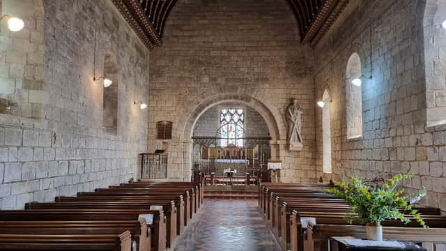 Interior of St Andrew's Church featuring wooden pews, stone walls, stained glass windows, and a decorative ceiling.