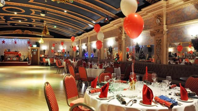 Elegant banquet hall decorated with red and white balloons, festive table settings, and holiday decor.