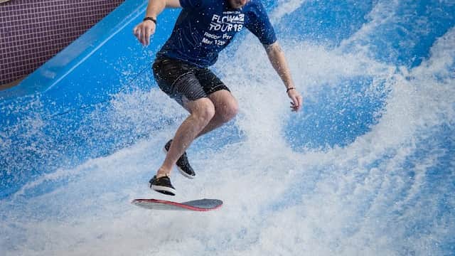 A man surfing on a flowboard in a wave pool at Redcar Leisure Centre, surrounded by splashing water.