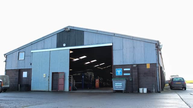 Large metal warehouse with an open front, featuring a sign for P A Blackburn Ltd, set in a rural area.