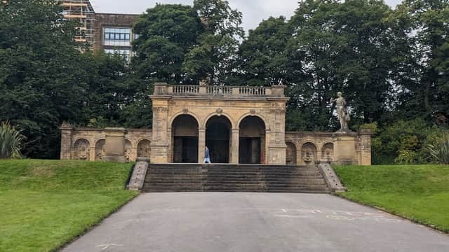 Historic stone structure with arches, steps, and a statue, surrounded by lush greenery in People's Park, Halifax.