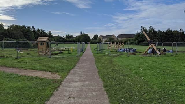 Pathway through Wickersley Park with construction barriers, grassy areas, and play equipment in the background.