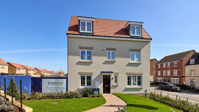 Modern three-story house with a red-tiled roof, surrounded by green grass and pathway, featuring a sign for Easymove.