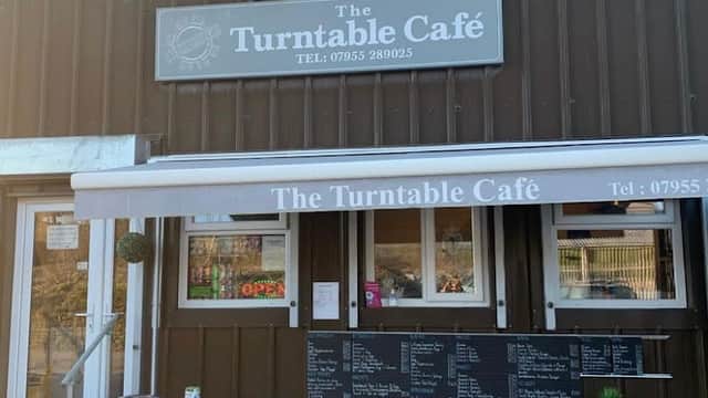 The Turntable Café features a rustic exterior, outdoor seating, and a menu board displayed prominently.
