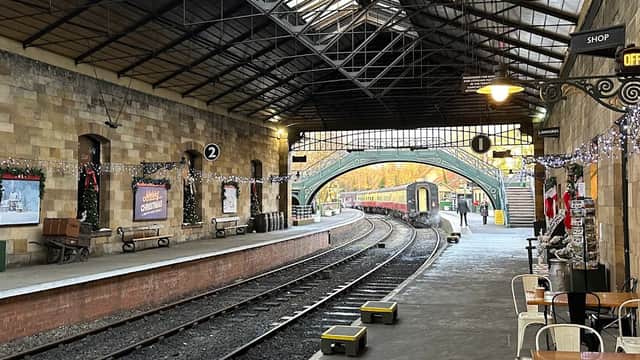 Historic railway station in Pickering, Yorkshire, featuring decorated platforms, tracks, and vintage train carriages.