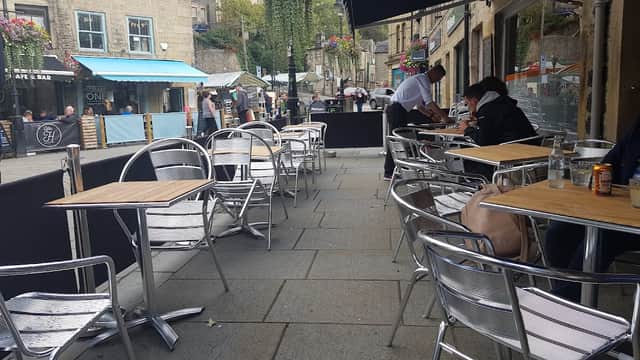 Outdoor seating area with metal chairs and tables, surrounded by shops and greenery in Chiserley, Yorkshire.