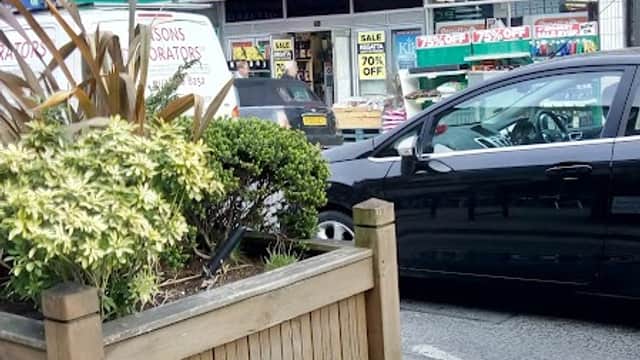 Yorkshire Trading Company storefront with green signage, potted plants, and parked cars in front.