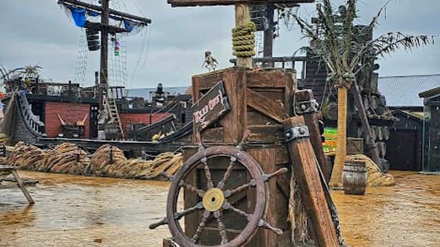 Signpost displaying "Pirate Show Times" with showtimes at 11:00, 1:00, and 3:00, set in a themed pirate area.