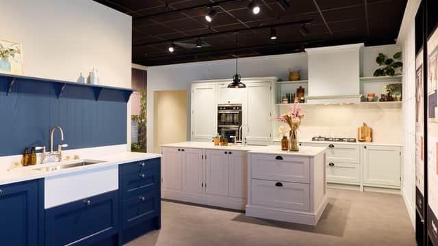 Modern kitchen display featuring blue and white cabinetry, a central island, and stylish decor elements.